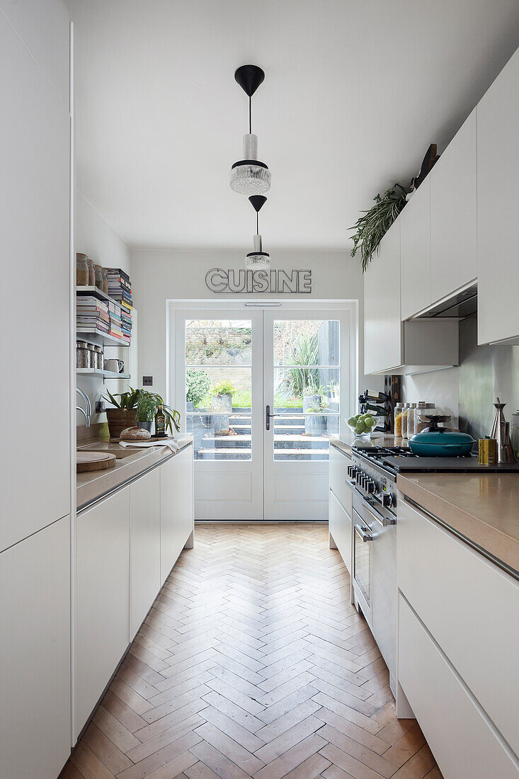 Bright kitchen with white cabinets and herringbone parquet flooring