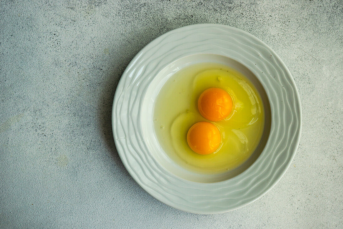 Zwei aufgeschlagene Eier auf Keramikteller