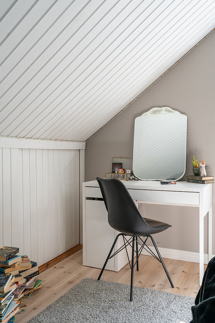 White table, mirror and black chair under a sloping roof