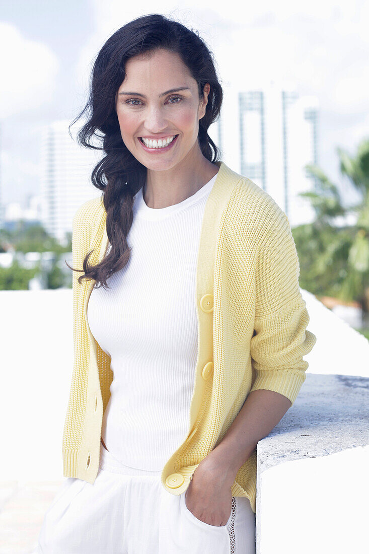 Dark-haired woman in white top and yellow cardigan