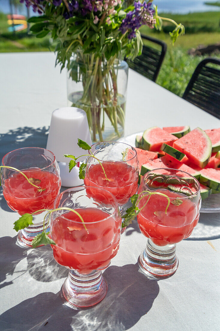 Wassermelonengetränk mit Minze auf Terrassentisch im Sommer