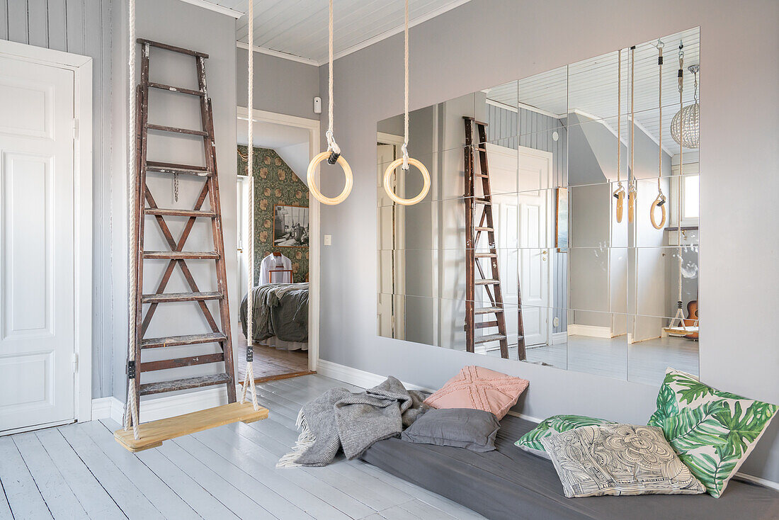 Room with mirror wall, ladder, swing, gymnastic rings, mattress and cushions