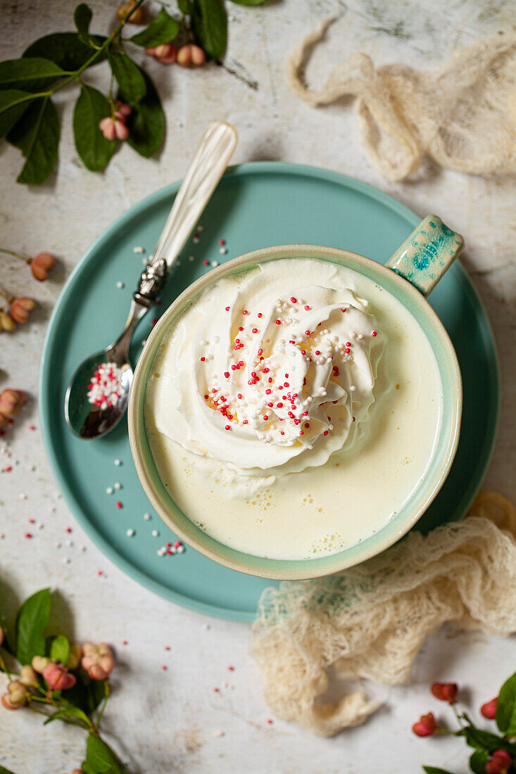 Eine Tasse heiße, weiße Schokoladen mit Sahne und Zuckerstreusel