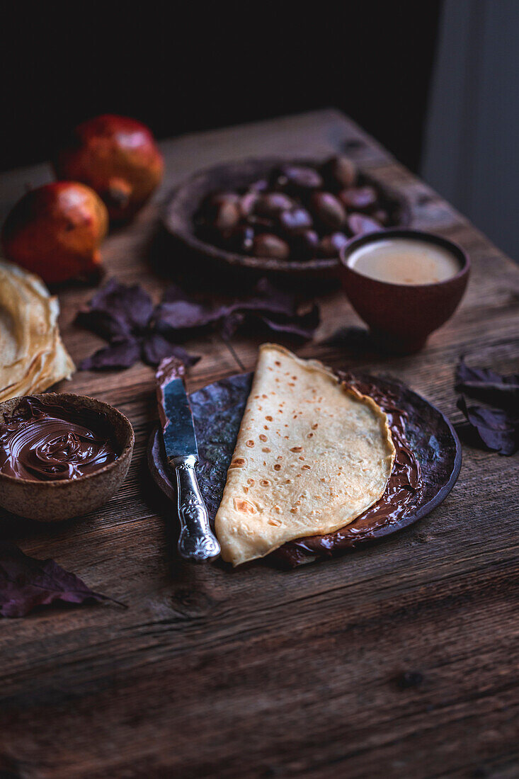 Crepes mit Schokoladenaufstrich auf rustikalem Holztisch