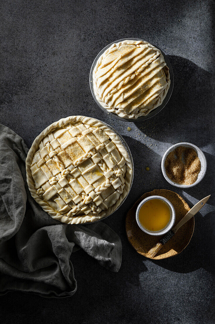 Two pies with lattice crust on dark neutral background