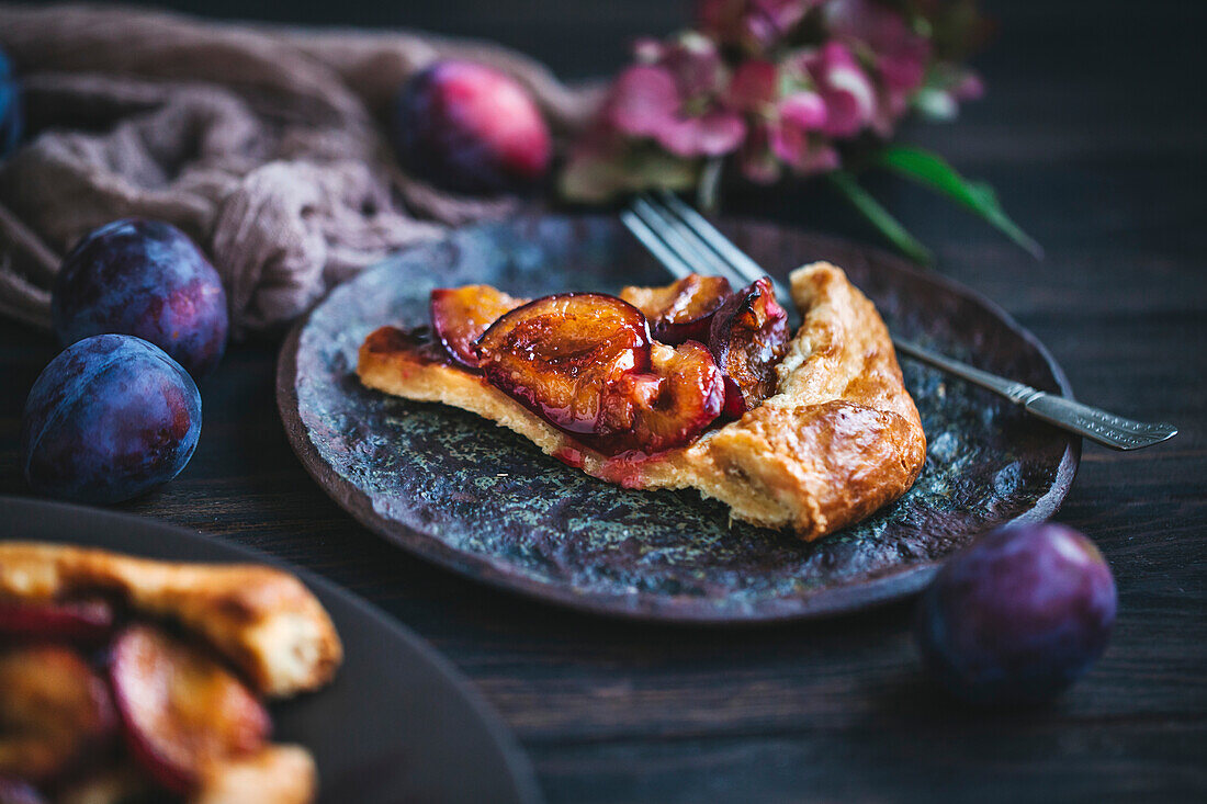 Slice of plum galette served on a ceramic dessert plate