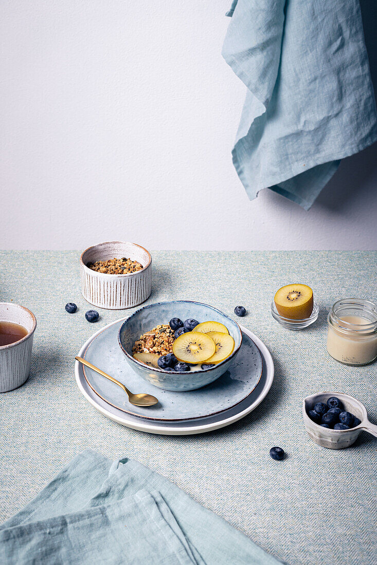 Müsli mit Heidelbeeren und Kiwischeiben in Keramikschale