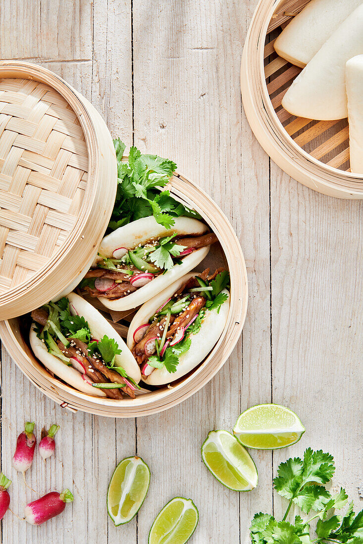 Tasty steamed baozi buns with radish and cucumber slices with meat and fresh cilantro on table