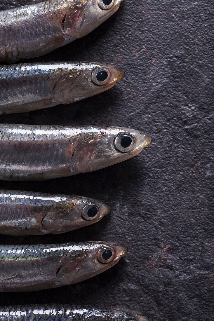 Raw anchovies lying on dark surface