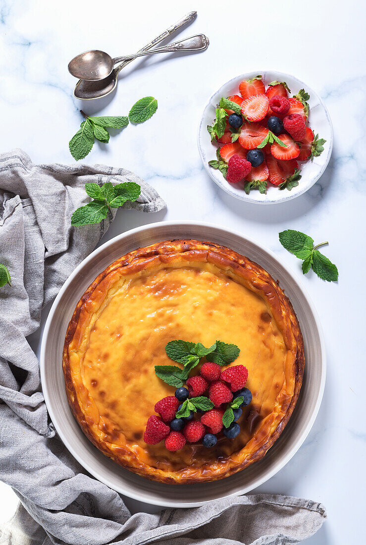 Käsekuchen dekoriert mit Himbeeren, Heidelbeeren und Minzblättern