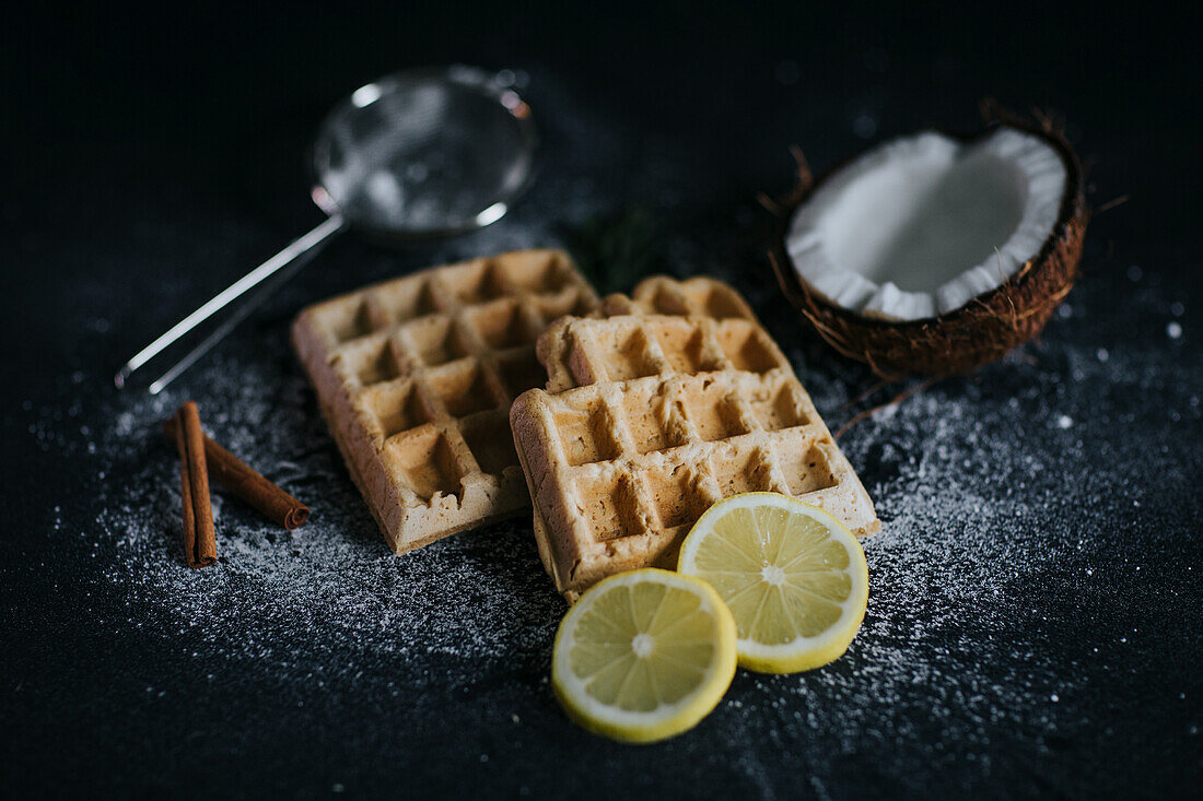 Vegan waffles served on black table with coconut and lemon slices