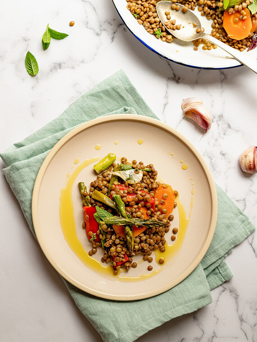 Lentil salad with vegetables and herbs served in plate on marble table