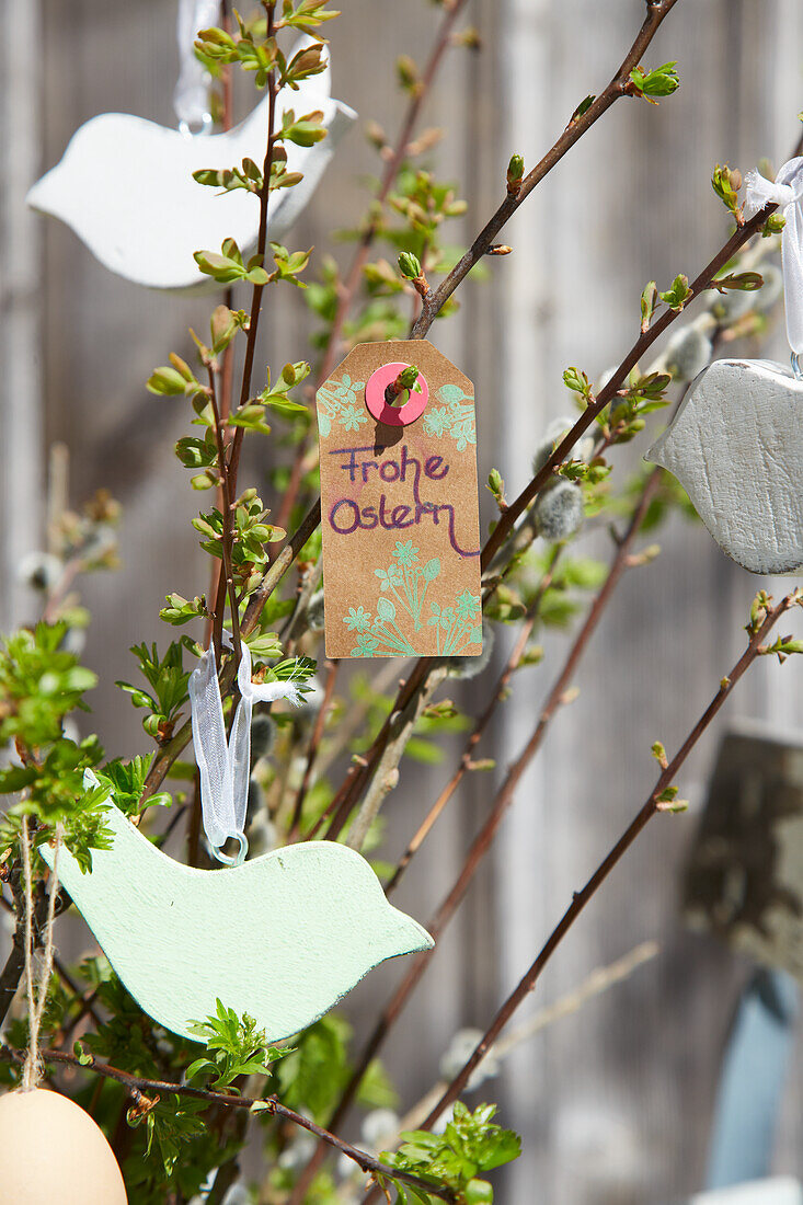 Spring branches with DIY birds made of modelling clay in a jug vase