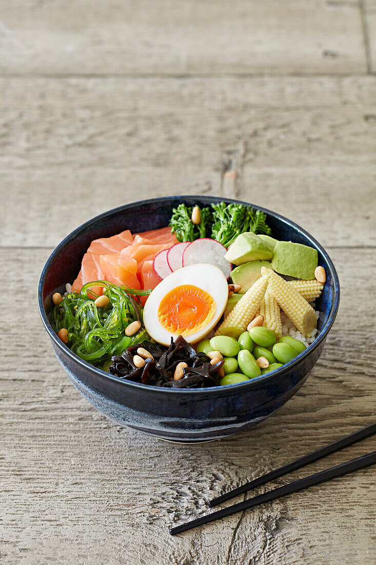 Poke Bowl mit Reis, Lachs, Algen, Gemüse und Ei