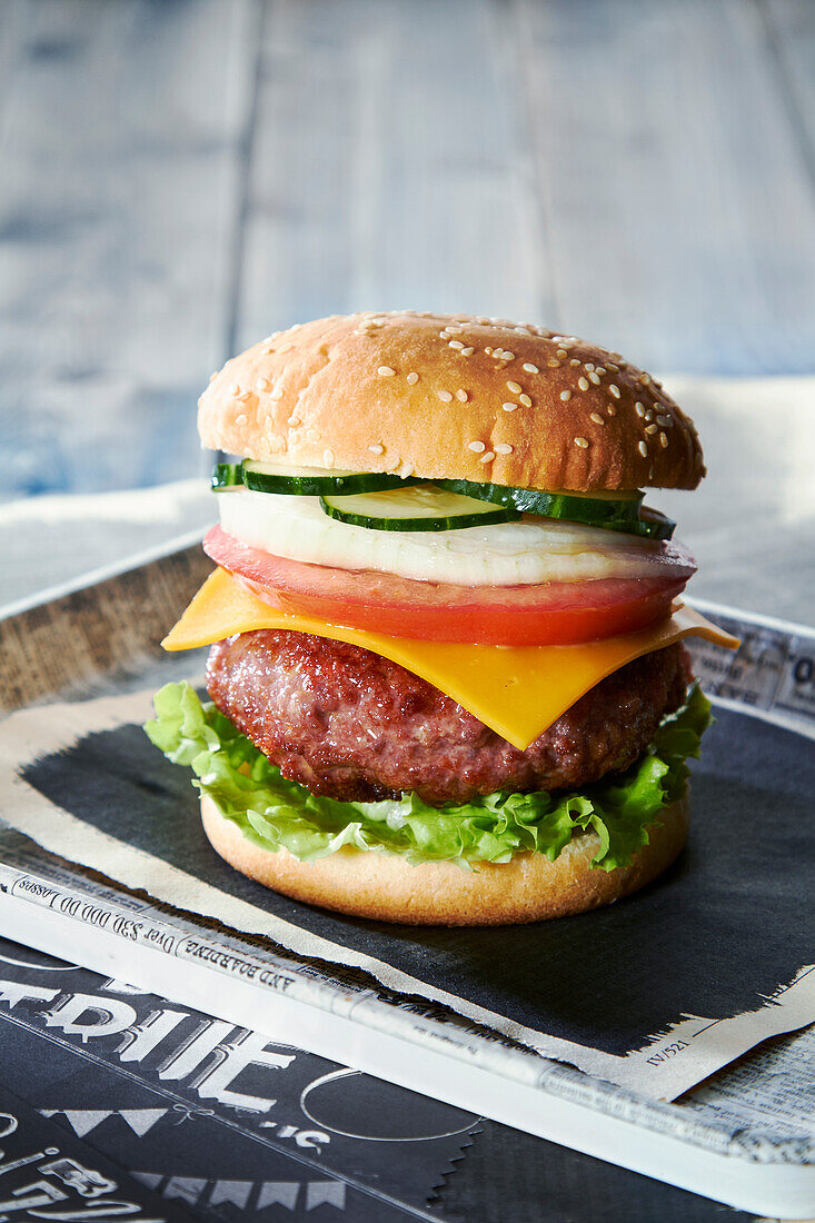 Burger mit Salatblatt, Käse, Tomate, Zwiebel und Gurke