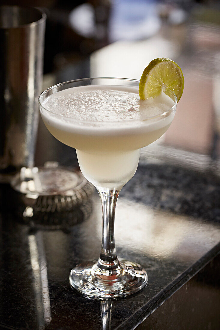 A white cocktail with lime wheel garnish