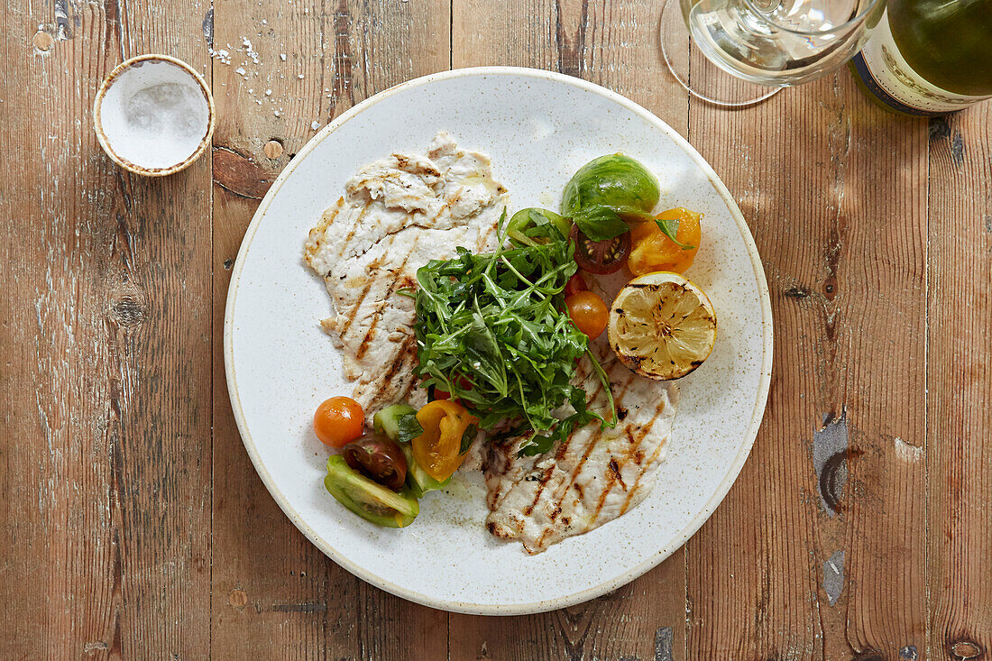 Flaches gegrilltes Hähnchenfilet mit Tomatensalat und Rucola