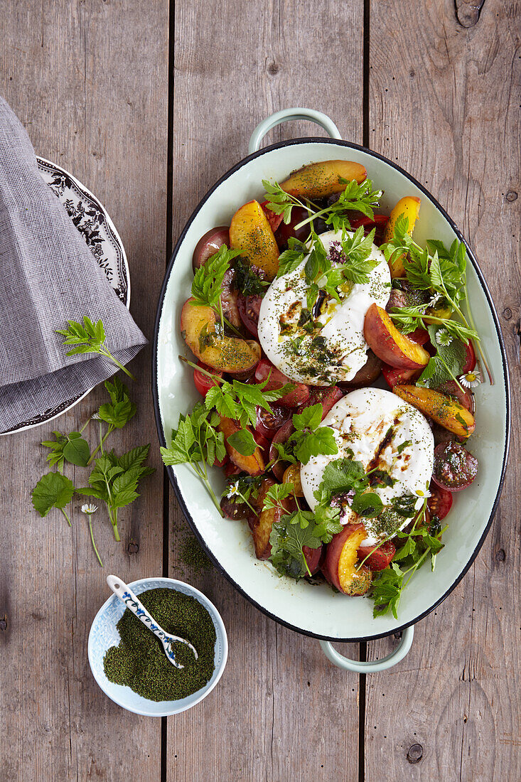 Caprese with peaches and wild herbs next to nettle seeds in a small bowl