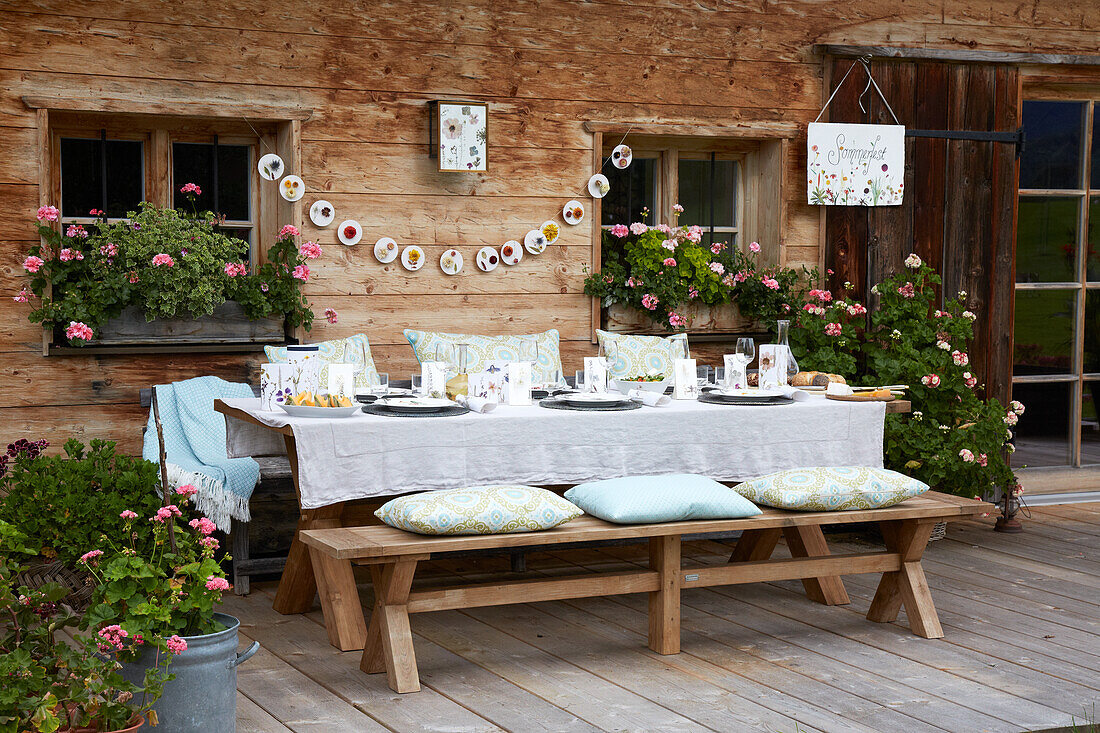 Festive table setting in front of a farmhouse with geraniums