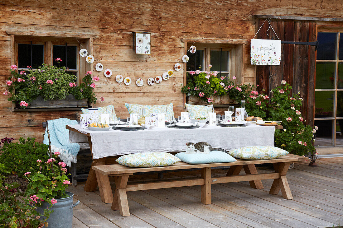 Gedeckter Tisch auf Terrasse, Katze und DIY-Girlande