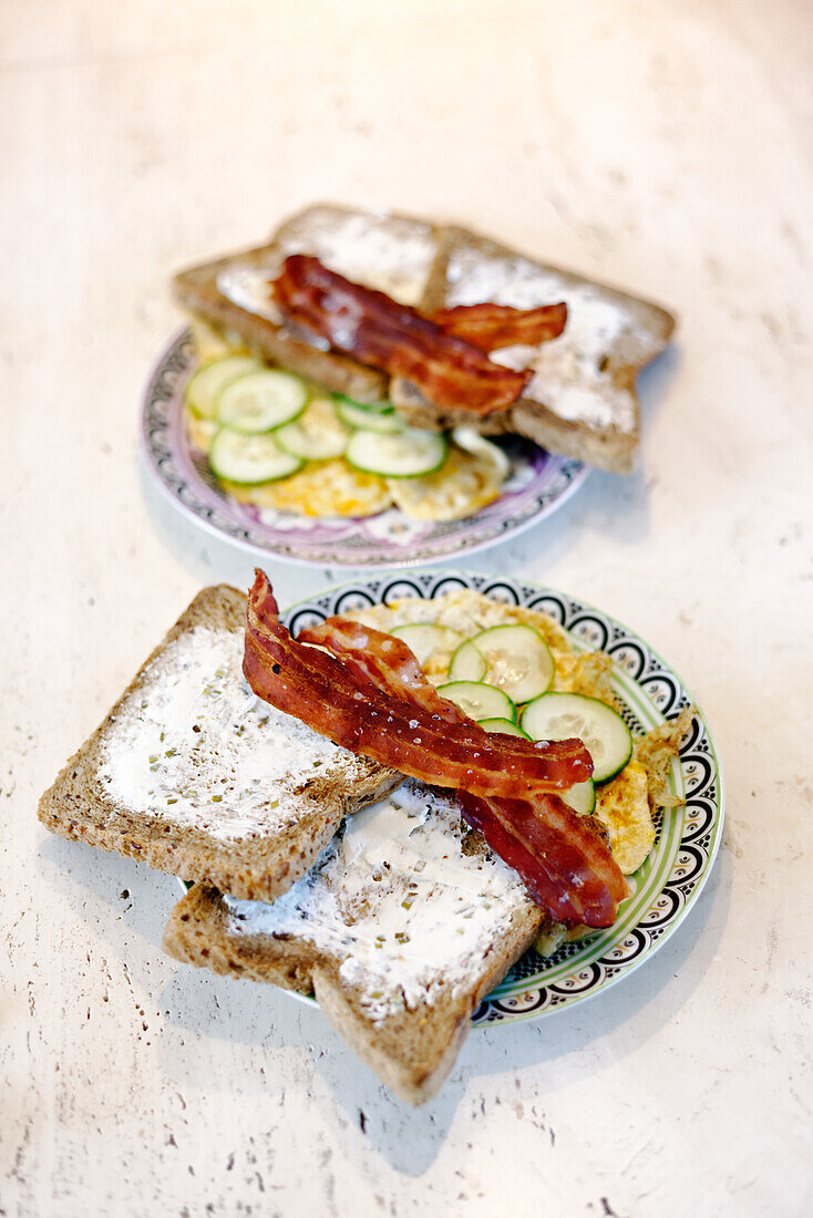 Omelet with cucumber slices, bacon, and toast with cream cheese