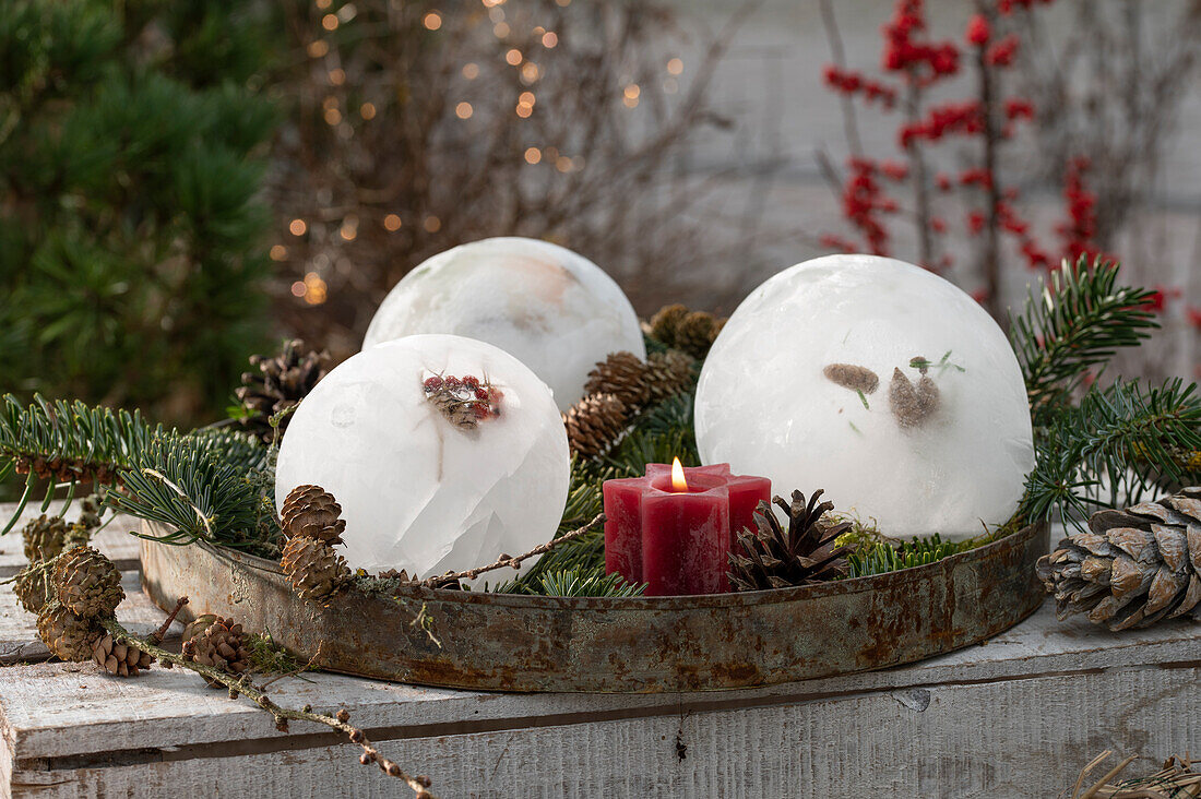Ice ball with rose hips, cones and red candle