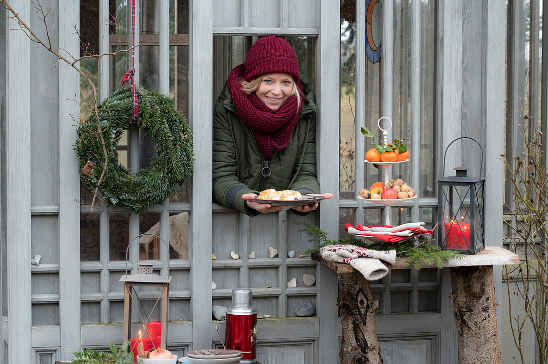 Woman dressed in winter handing plate with strudel through window