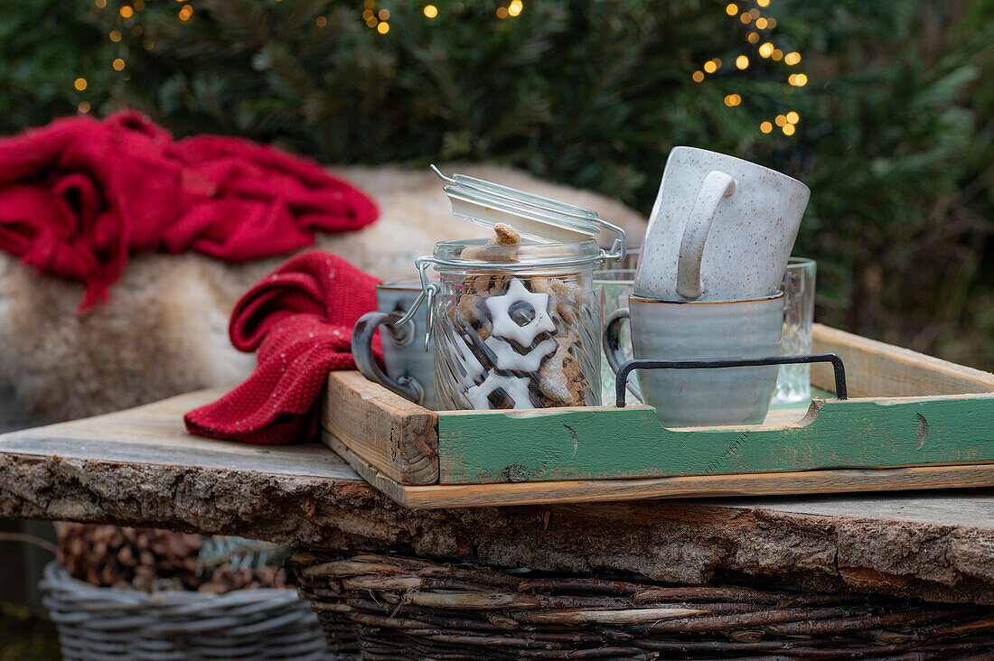 Glass with cinnamon stars and ceramic mug on wooden tray