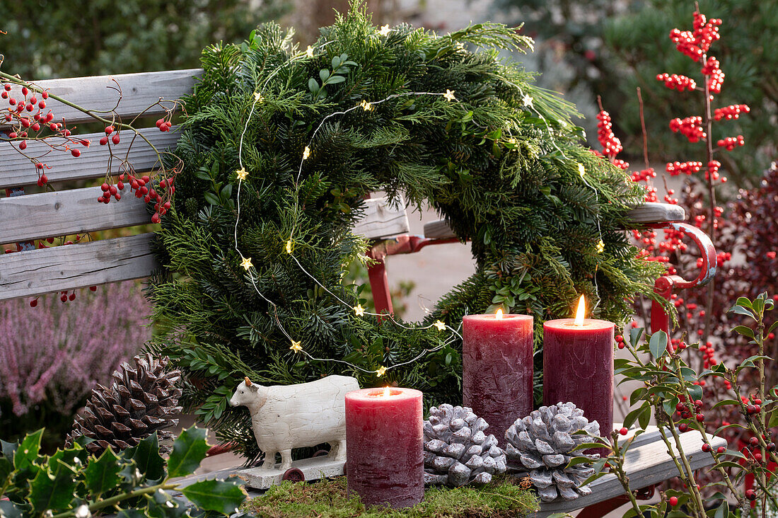 Wreath of mixed branches and candles on a garden bench