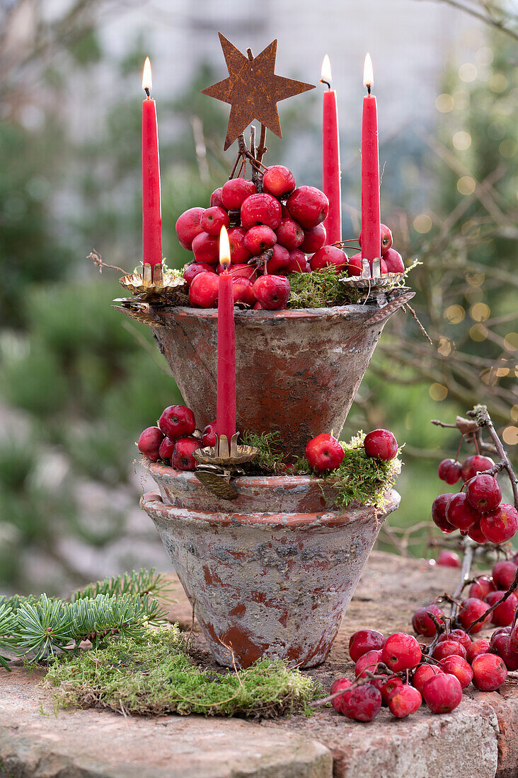 Tower of terracotta pots with ornamental apples and candles as Advent wreath