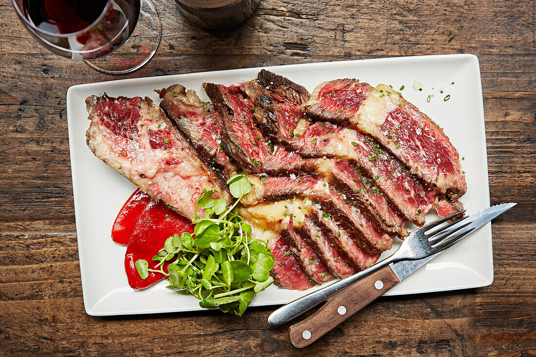 Rare Steak-Scheiben serviert mit einem Glas Rotwein