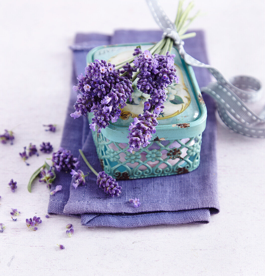 A mint-coloured jewelery box with a bouquet of lavender on a purple linen cloth