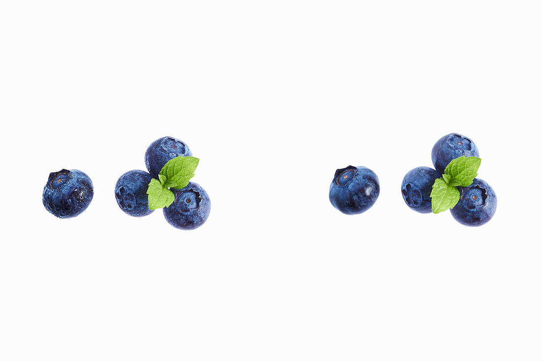 Some blueberries with leaves on white background