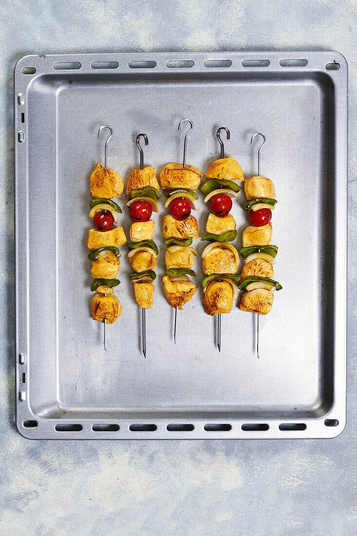 Chicken skewers with pepper, onion, and tomato on a metal tray