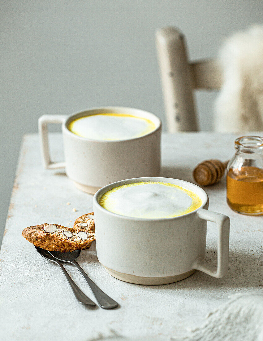 Goldene Milch in zwei Tassen serviert mit Cantuccini