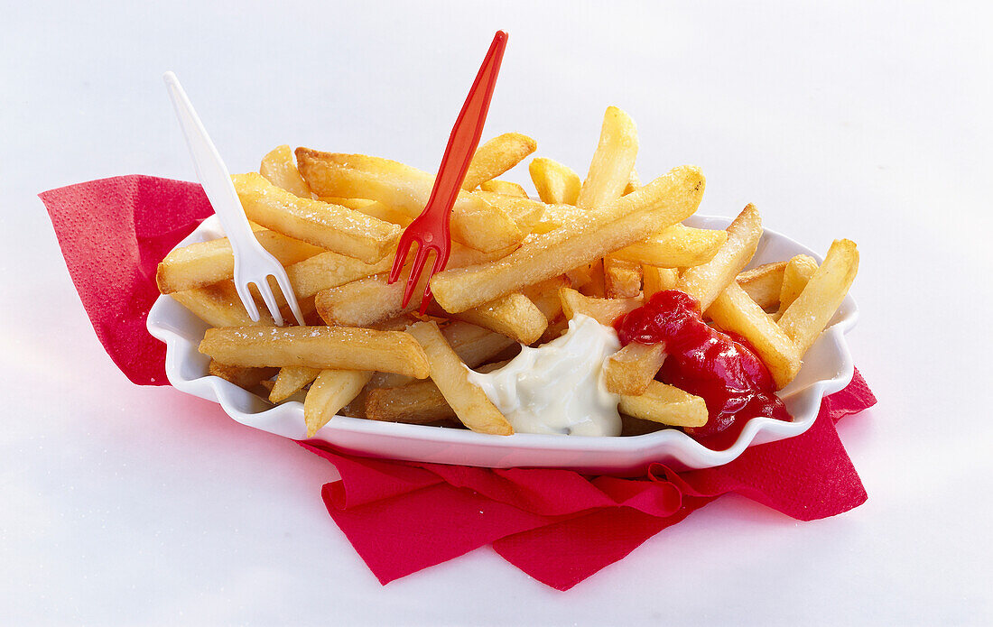 Bowl with French fries, mayonnaise and ketchup on a red napkin