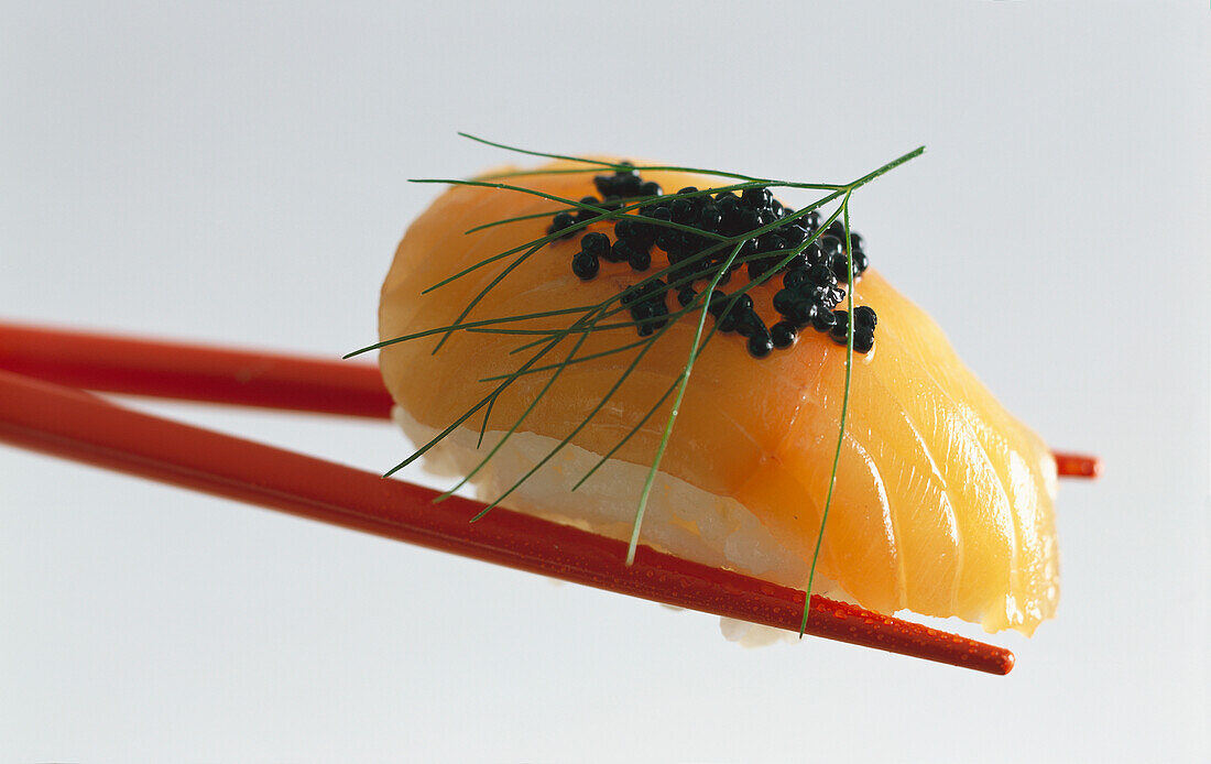 Nigiri-Sushi mit Lachs und Kaviar auf roten Essstäbchen