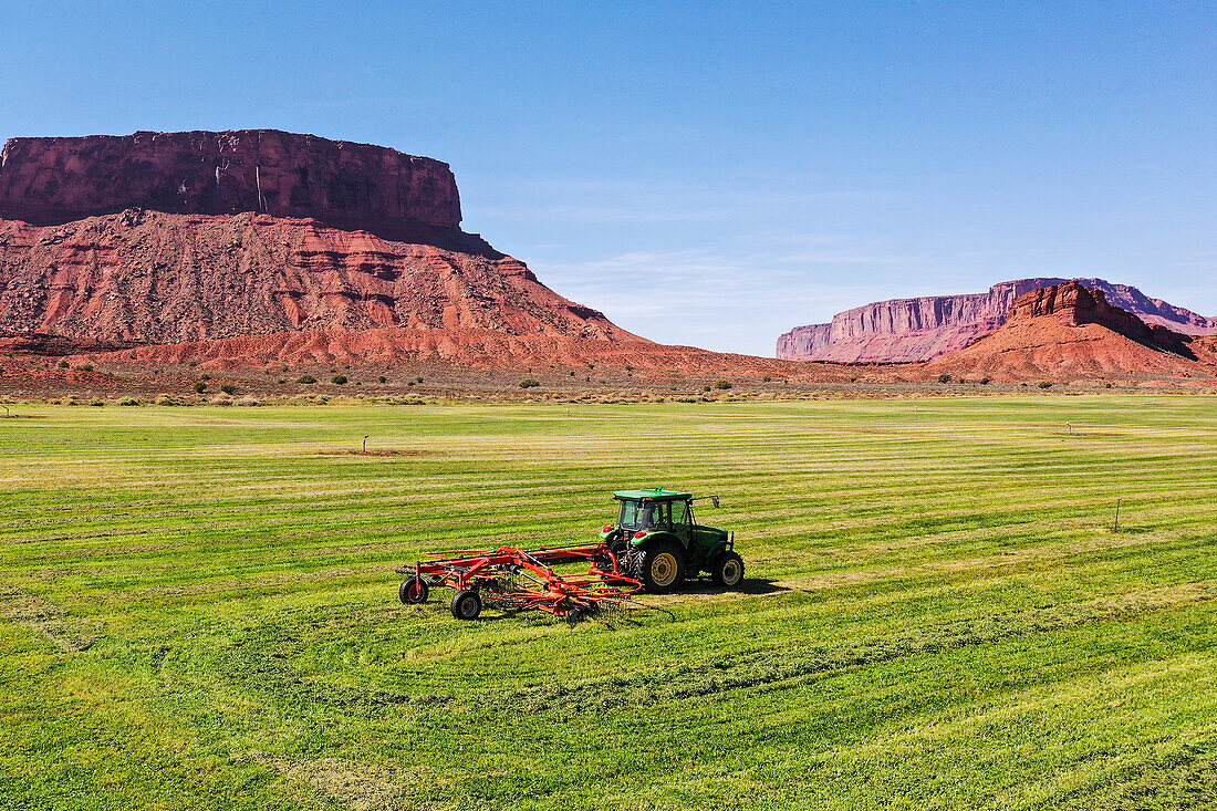 Rotary rake behind a tractor on a scenic ranch