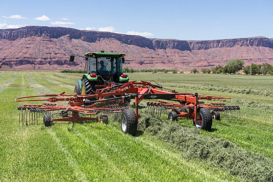 Rotary rake behind a tractor on a scenic ranch in Utah, USA