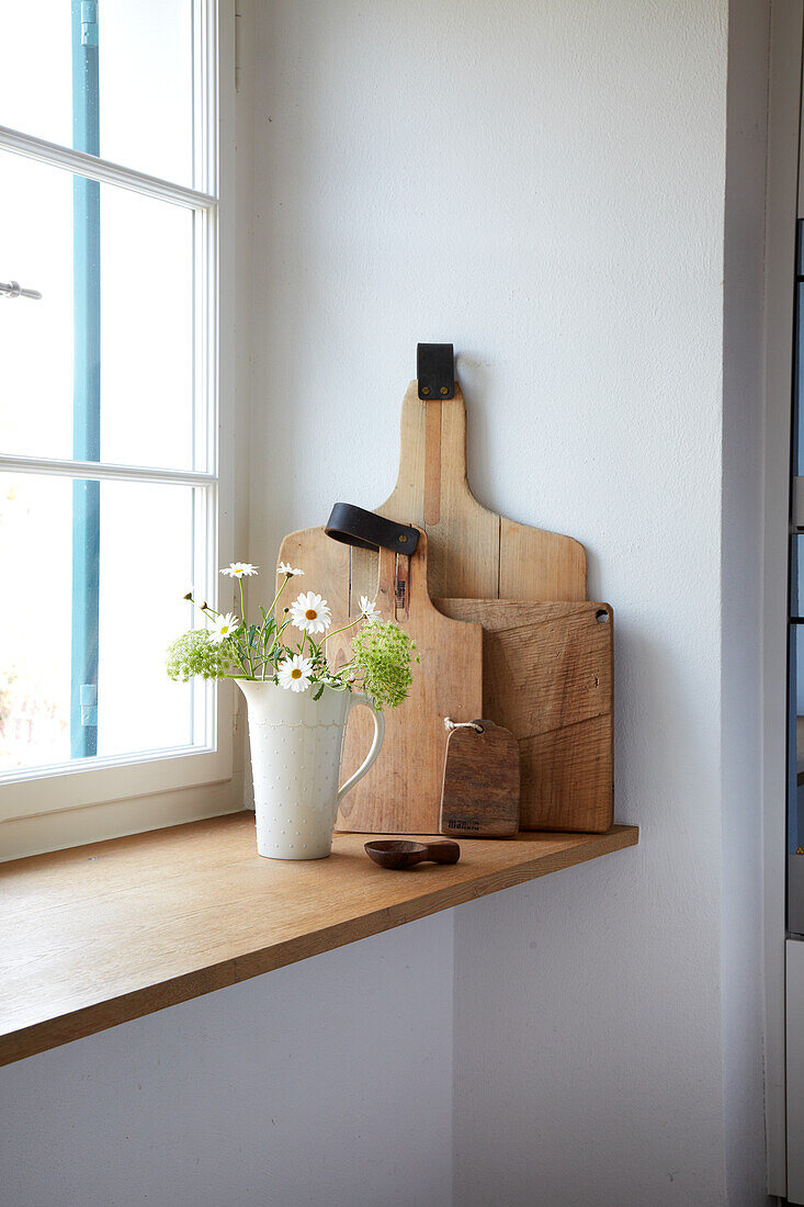 Holzbretter und Vase mit Wildblumen auf Fensterbrett