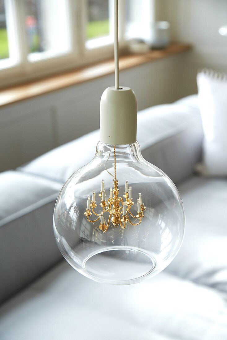 Pendant light with miniature chandelier above grey sofa