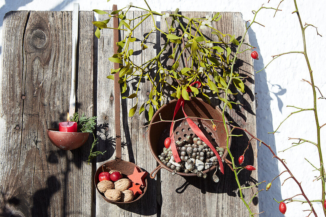 Winter decoration in old ladles with rosehips and nuts on a wooden wall