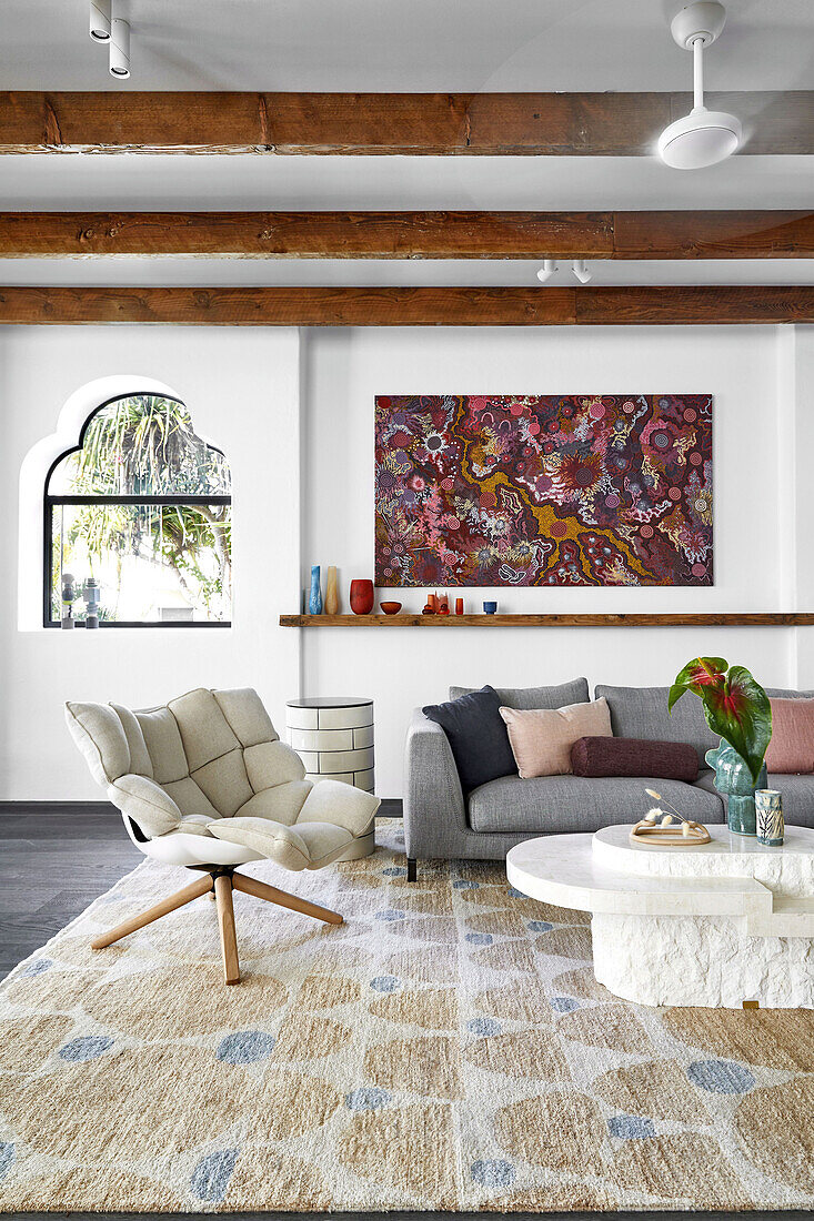 Living room with designer armchair, coffee table and sofa with modern art