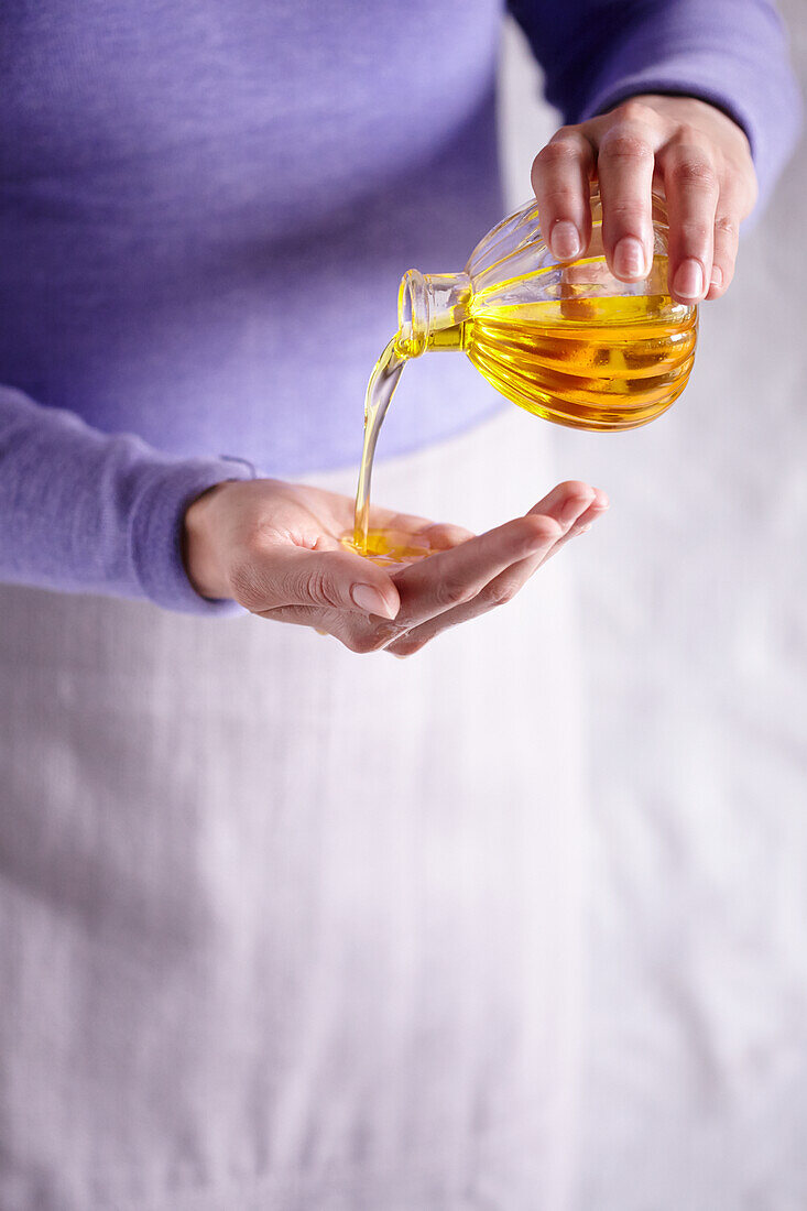 Frau gießt Aromaöl aus einem Flacon in ihre Hand