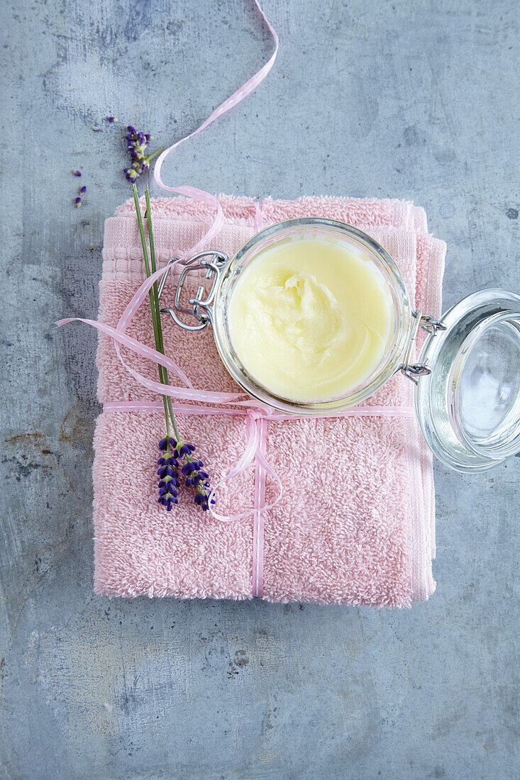 Cream jar and lavender blossoms on a pink towel