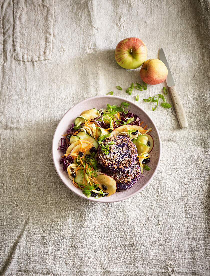 Raw vegetable salad with red cabbage patties, apples, and tahini dressing