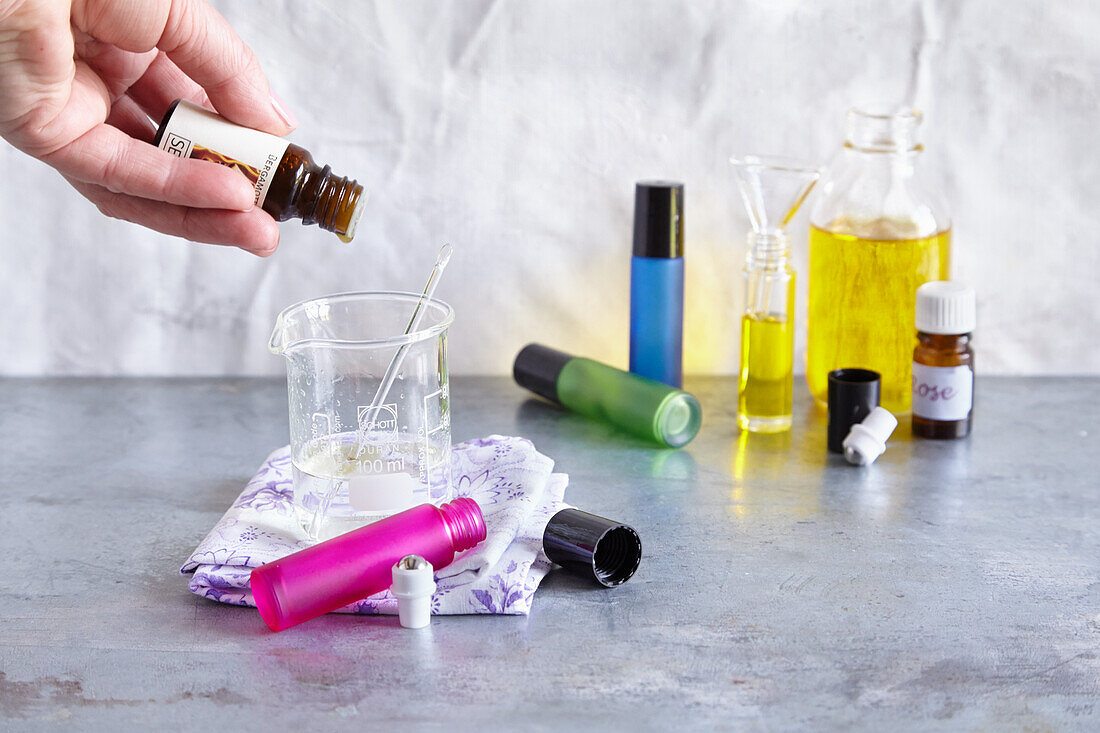Empty roll-on bottles, ingredients for the roll-ons are mixed in a medicinal glass beaker