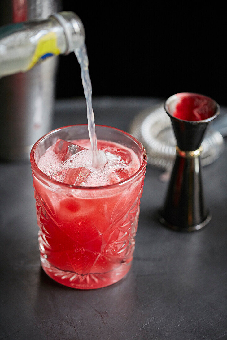 A red cocktail in a glass with ice cubes