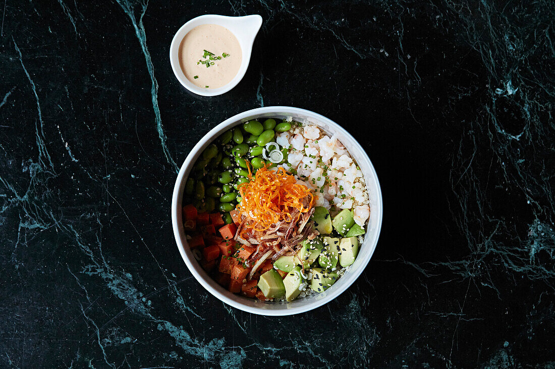 A healthy bowl with avocado, carrot, edamame and seafood