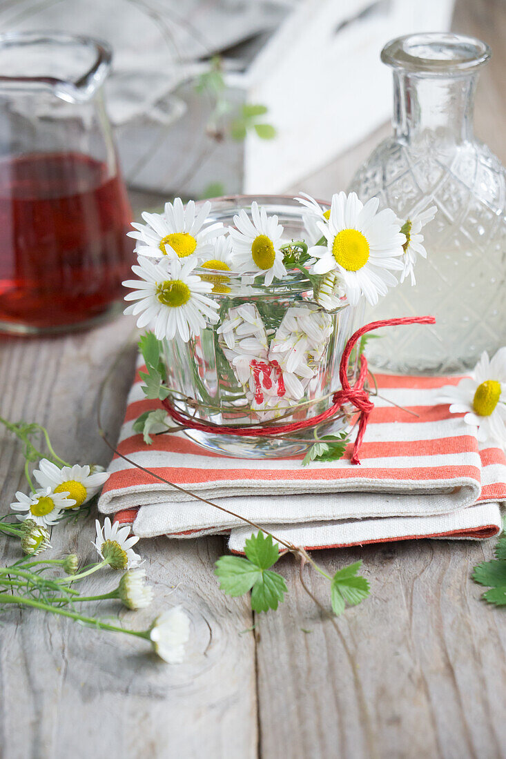 Glass votive holder, decorated with a heart of chamomile blossoms, printed with an initial, and red rope